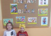 Dzieci z grupy Żabki w przebraniu za Elzę i Kubusia Puchatka z książeczkami pozują do zdjęcia.