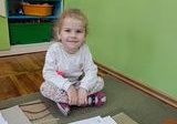 Dziecko z grupy Misie uklada na dywanie puzzle z bajkowym obrazkiem.