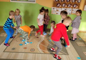 Grupa Misie na dywanie podczas zabawy ruchowej. Dzieci zbierają emblematy kropelek.