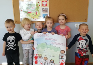 Dzieci trzymają plakat z Kodeksem Małego Patrioty.