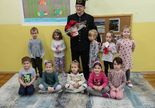 Dzieci wraz z górnikiem ustawieni są do pamiątkowego zdjęcia. Górnik trzyma w ręku betlejemską gwiazdę podarowaną w podziękowaniu za przybycie na spotkanie z przedszkolakami.