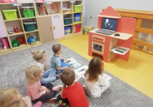 Dzieci siedzą przed laptopem i oglądają film.