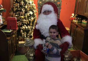 Święty Mikołaj i chłopiec trzymający prezent, który dostał od Świętego Mikołaja.