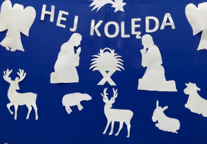 Zdjęcie przedstawia niebieską dekorację z białym napisem „Hej kolęda” i Bożonarodzeniowymi elementami.