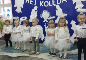 Dzieci stoją przed dekoracją z okazji Świąt Bożego Narodzenia i mówią wierszyk.