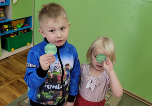 Chłopiec z dziewczynką trzymają się za rączki i pokazują dwa takie same guziki