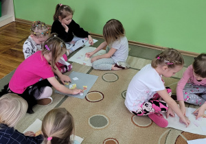 . Dziewczynki siedzą w parach na dywanie i układają puzzle