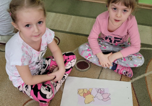 . Dwie dziewczynki prezentują ułożony obrazek Kubusia Puchatka i Prosiaczka