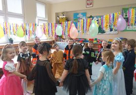 Dzieci tańczą w kole do muzyki karnawałowej.