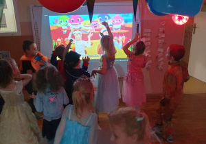Dzieci z grupy Smerfy tańczą do piosenki Baby Shark, która jest wyświetlana na tablicy interaktywnej.