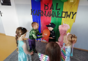 Dzieci stoją w kole i podają sobie balon.
