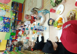 Dzieci z grupy Stokrotki siedzą przy stole i zajadają przygotowany poczęstunek.