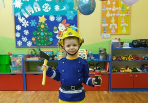 Chłopiec prezentuje swój strój strażaka.