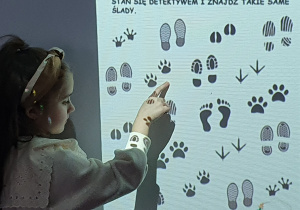 Dziewczynka wciela się w zawód detektywa i na tablicy interaktywnej wskazuje takie same ślady.