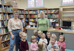 Uśmiechnięte i zadowolone dzieci pozują do zdjęcia wspólnie z Panią z biblioteki szkolnej.