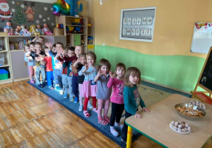 Dzieci z grupy Biedronki pozują do zdjęcia stojąc w kolejce do przedszkolnej Piekarni.