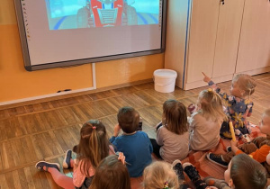 Dzieci oglądają bajkę wyświetlaną na tablicy multimedialnej.