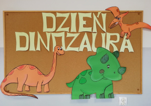 Tablica z napisem Dzień Dinozaura i papierowymi konturami dinozaurów.