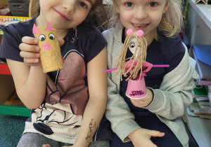 Dwie dziewczynki pozują do zdjęcia trzymając w rękach wcześniej zrobione zabawki