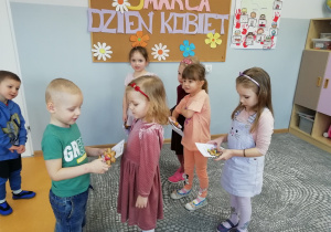 Chłopczyk wręcza dziewczynce upominek z okazji Dnia Kobiet.
