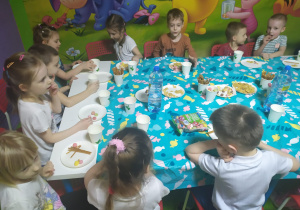 Dzieci grupy Pszczółki z okazji dnia kobiet były w Figloraju. Na zdjęciu chłopcy i dziewczynki siedzą przy stole podczas słodkiego poczęstunku.