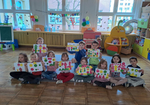 Dzieci pozują do zdjęcia grupowego ze swoimi pracami, które tworzyły z figur geometrycznych.
