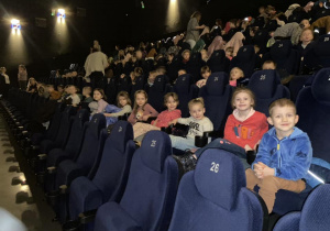 Dzieci z grupy Żabki oraz inne przedszkolaki siedzą na fotelach kinowych w oczekiwaniu na rozpoczęcie bajki „Wróżka Zębuszka”.