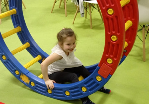 Zdjęcie przedstawia dziewczynkę w białej bluzce siedzącą w plastikowym kole.