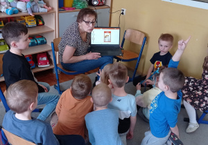 Przedszkolaki oglądają prezentacje o emocjach wyświetlaną na monitorze laptopa.