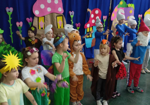 Dzieci przebrane w stroje smerfów i biedronek, motyli i drzew śpiewają wiosenną piosenkę.
