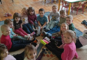 Dzieci z grupy Biedronki pozują do zdjęcia siedząc na dywanie w kolorowych skarpetkach.