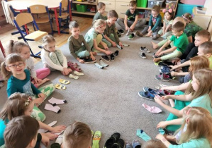 Dzieci z grupy Odkrywcy biorą udział w zabawie Kto szybciej założy skarpetki.