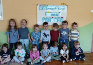 Dzieci z grupy Biedronki pozują do zdjęcia na tle tablicy z napisem Światowy Dzień Autyzmu.