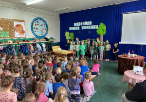 grupa dzieci w zielonych podkoszulkach spiewa piosenkę.