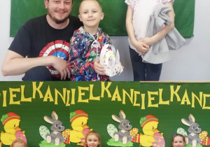 Cztery zdjęcia z dziećmi, które trzymają papierowe koszyczki ze styropianowym udekorowanym jajkiem.