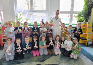 Dzieci pozują do zdjęcia z ciocią Pleciugą trzymając w dłoniach swoje króliki