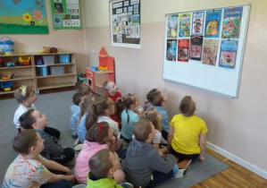 Dzieci z grupy Tropiciele słuchają wiadomości o najpopularniejszych bajkach i oglądają ich okładki.