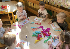 Przedszkolaki wykonują tęcze – jeden z symboli autyzmu przy użyciu kolorowej bibuły.