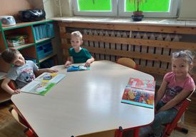 Dzieci oglądają książeczki wypożyczone z biblioteczki w swojej sali.
