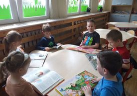 Dzieci oglądają książeczki wypożyczone z biblioteczki w swojej sali.