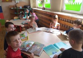 Dzieci oglądają książeczki wypożyczone z biblioteczki w swojej sali.
