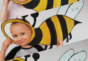 Witraż przedstawiający dwie dziewczynki i chłopca w ramce w kształcie pszczoły.