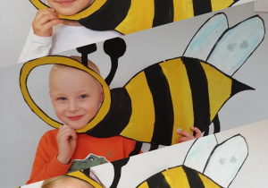 Witraż przedstawiający troje dzieci – chłopca i dwie dziewczynki w ramce w kształcie pszczoły.