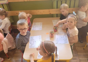 Stokrotki przy stoliku kolorują obrazek zgodnie z opisem opowiadania.