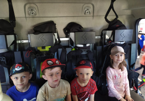 Czwórka dzieci siedzi w wozie strażackim.
