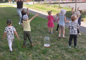 Dzieci z grupy Krasnale łapią bańki mydlane podczas zabawy na dworze.