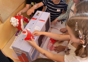 Dzieci z grupy Żabki rozpakowują pudełko z nagrodami.