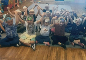 Dzieci z grupy Żabki pozują do zdjęcia w opaskach kropkowych trzymając się za ręce.