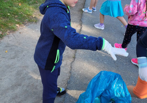 Chłopiec wrzuca śmieci do niebieskiego worka.