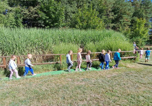 Dzieci przechodzą po zielonej ścieżce.
